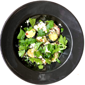 Recette de courgettes à la fêta façon sarladaise. On peut voir les courgettes, la feta, du persil plat ou encore du lard. 