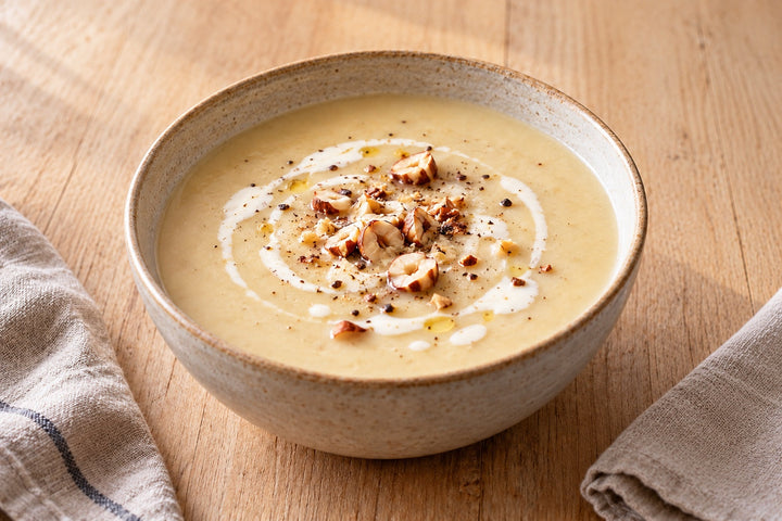 Velouté d'endives crème dans un bol, noisettes grillées concassées et filet de crème
